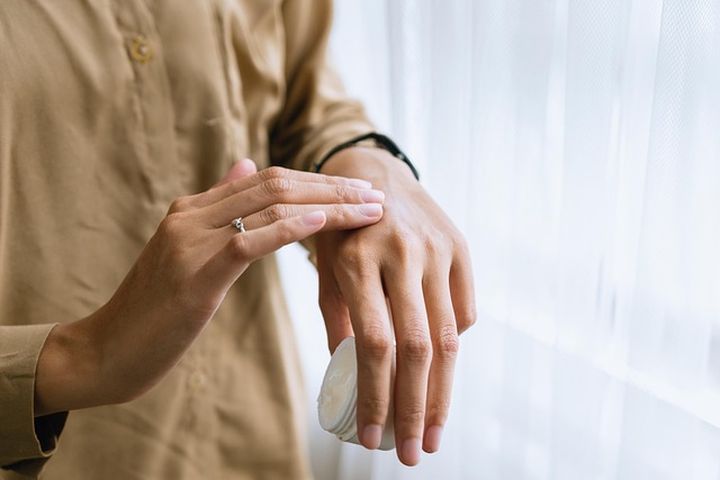 Hände, die Creme auf den Handrücken auftragen